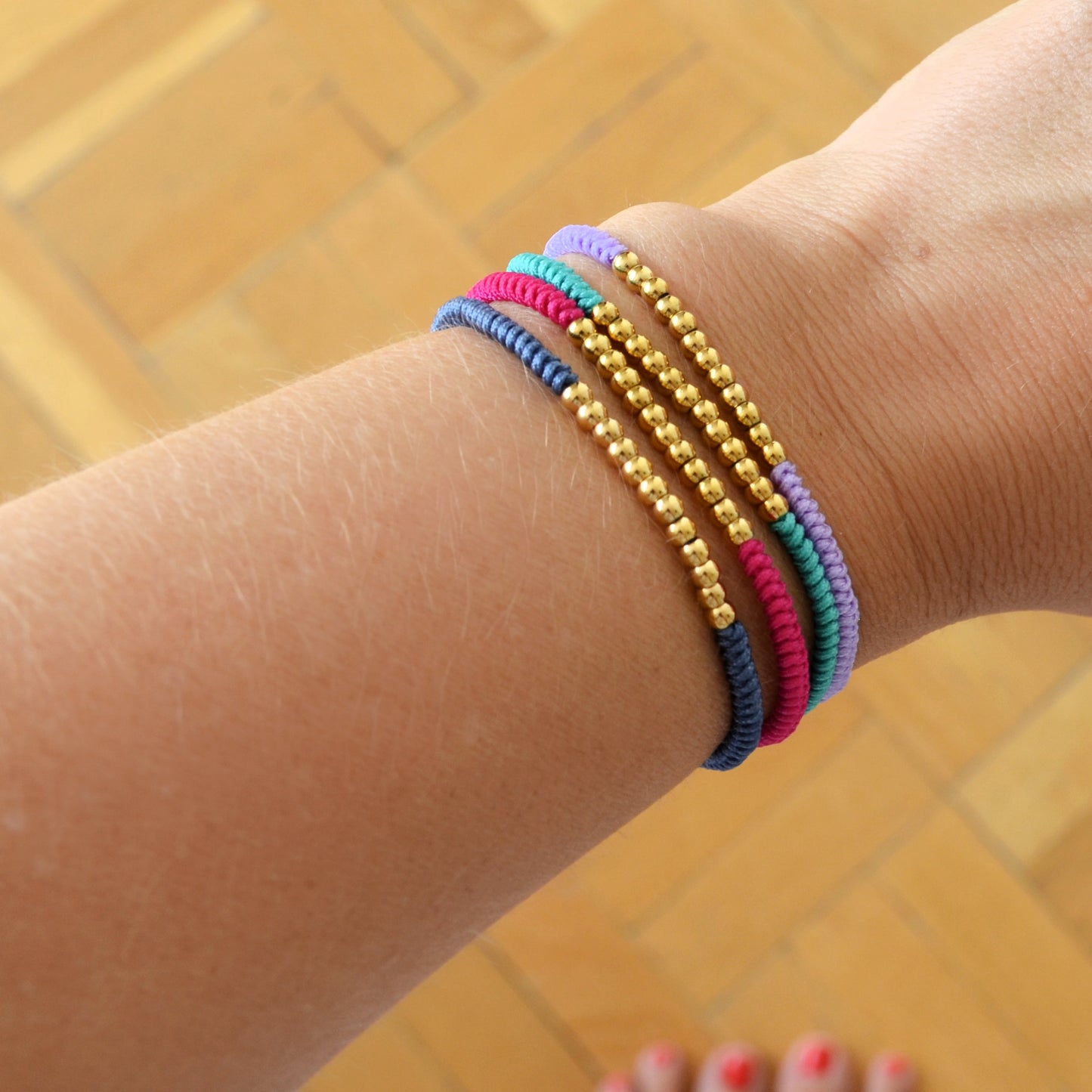 pulsera de hilo trenzado en colores con bolitas doradas. el material es acero hipoalergénico resistente al agua.Gold plated stainless steel waterproof bead colorful braid bracelet