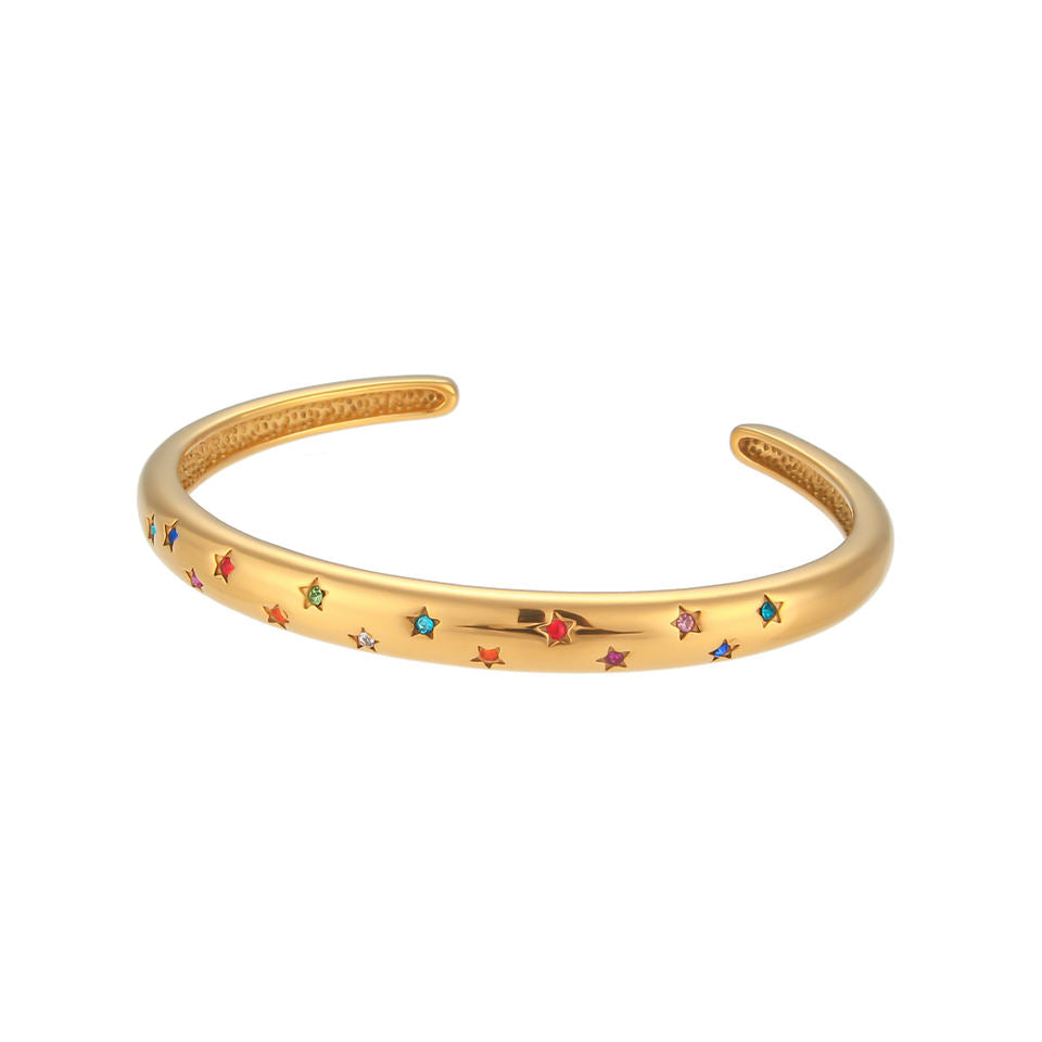 Pulsera o brazalete rígido tipo esclava resistente al agua. Está confeccionado en acero inoxidable con baño de oro 18 kilates o plata rodiada. tiene circonitas en forma de estrellas.Gold plated stainless Steel stiff or rigid waterproof rainbow zircon star bangle bracelet.