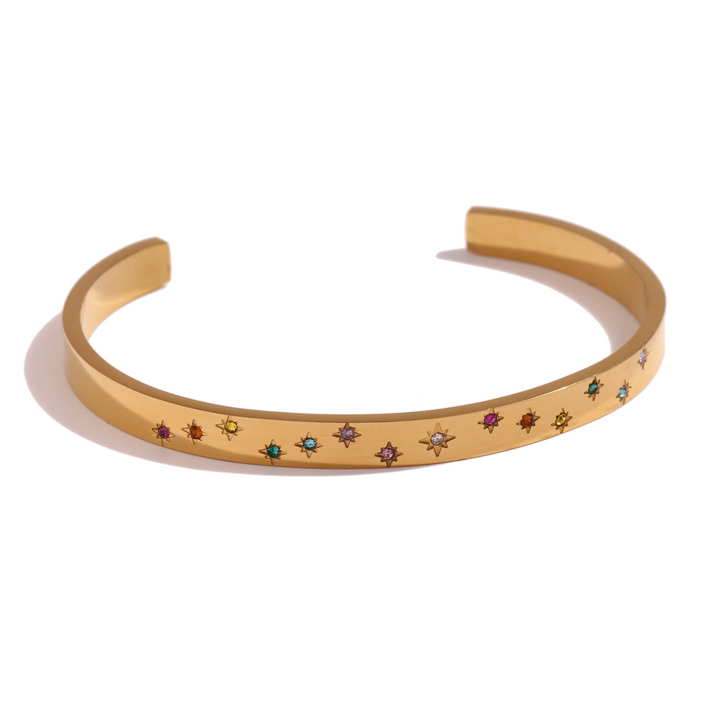 Pulsera o brazalete rígido tipo esclava resistente al agua. Está confeccionado en acero inoxidable con baño de oro 18 kilates o plata rodiada. tiene circonitas en forma de estrellas.Gold plated stainless Steel stiff or rigid waterproof rainbow zircon star bangle bracelet.
