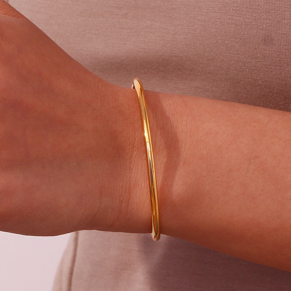 Pulsera o brazalete rígido y fino tipo esclava resistente al agua. Está confeccionado en acero inoxidable con baño de oro 18 kilates o plata rodiada. Gold plated stainless Steel stiff or rigid waterproof thin bracelet.