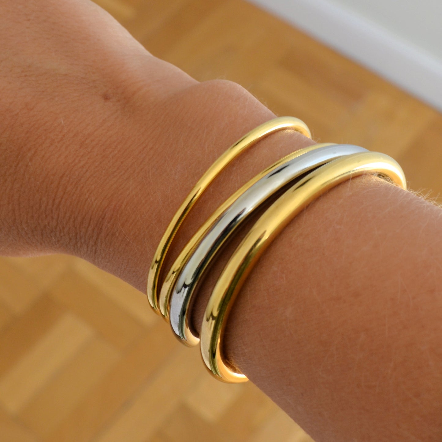 Pulsera o brazalete rígido tipo esclava resistente al agua. Está confeccionado en acero inoxidable con baño de oro 18 kilates o plata rodiada. Gold plated stainless Steel stiff or rigid waterproof bracelet.