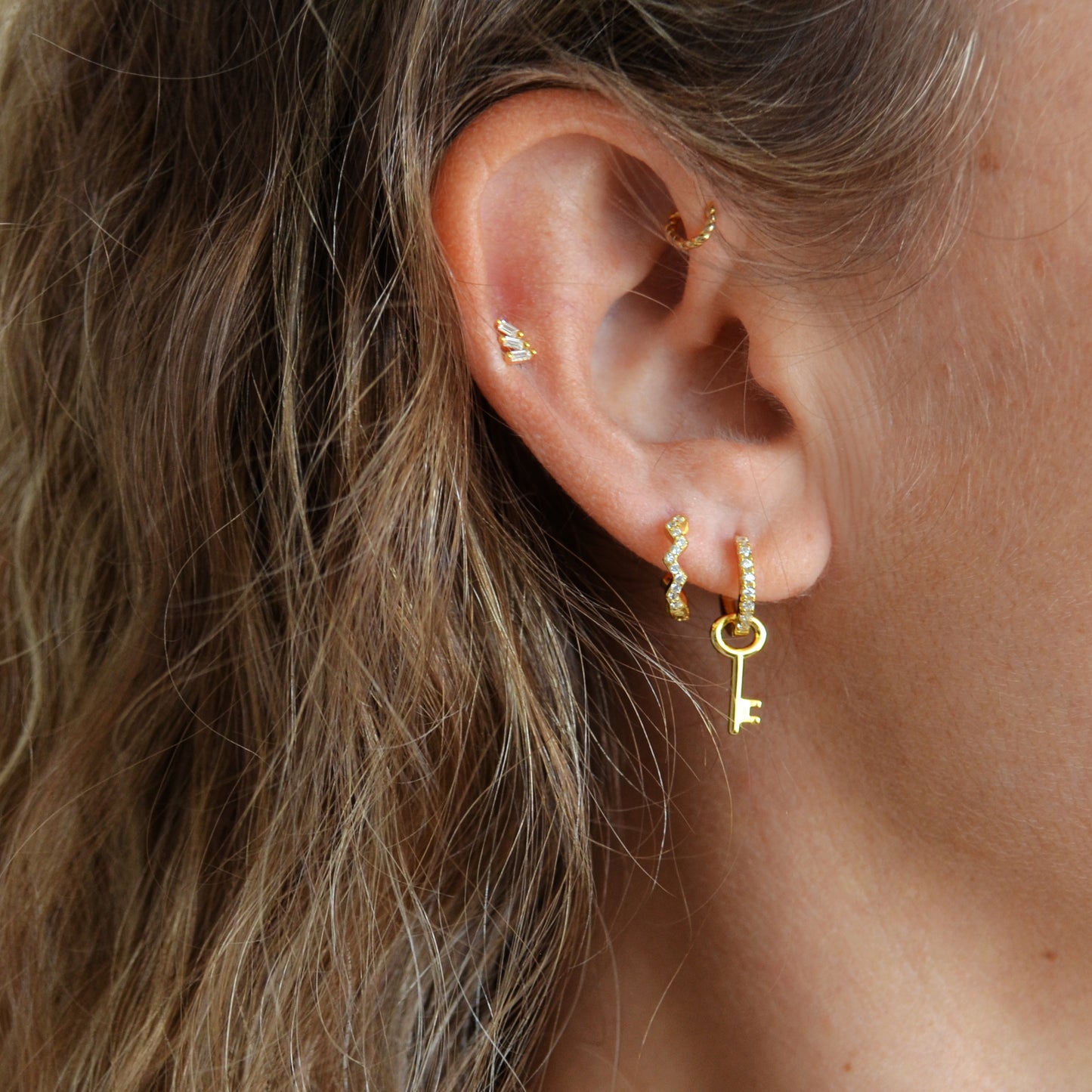 pendientes de aro en forma de zig zag que imita un piercing. Está confeccionado en plata de ley con baño de oro 18 kilates y circonitas. gold plated sterling silver zig zag zircon hoop earrings