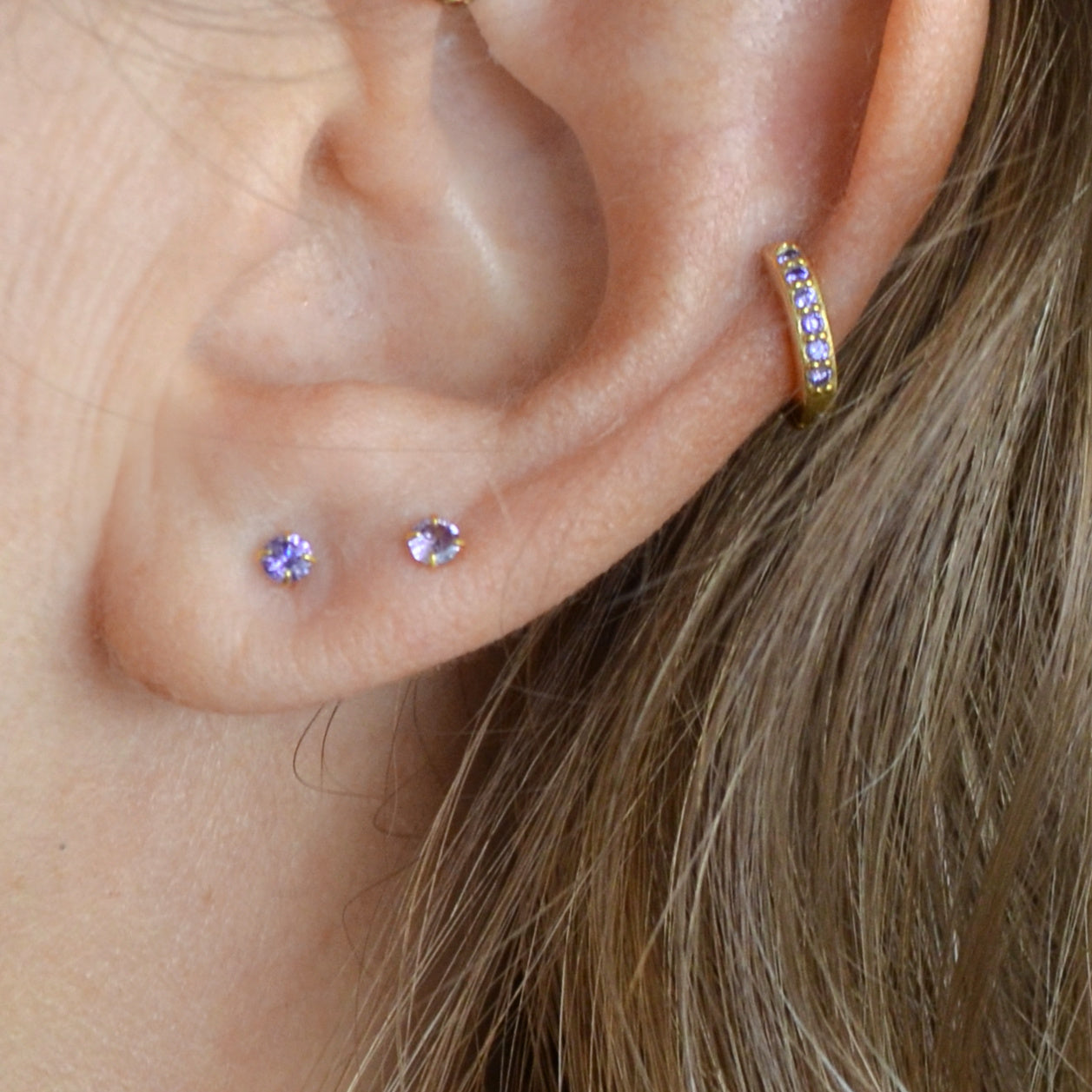 Pequeños pendientes de aro con circonitas lila o moradas confeccionados en plata de ley 925 con baño de oro 18 kilates. Gold plated silver hoop earrings for piercing with lilac zircon
