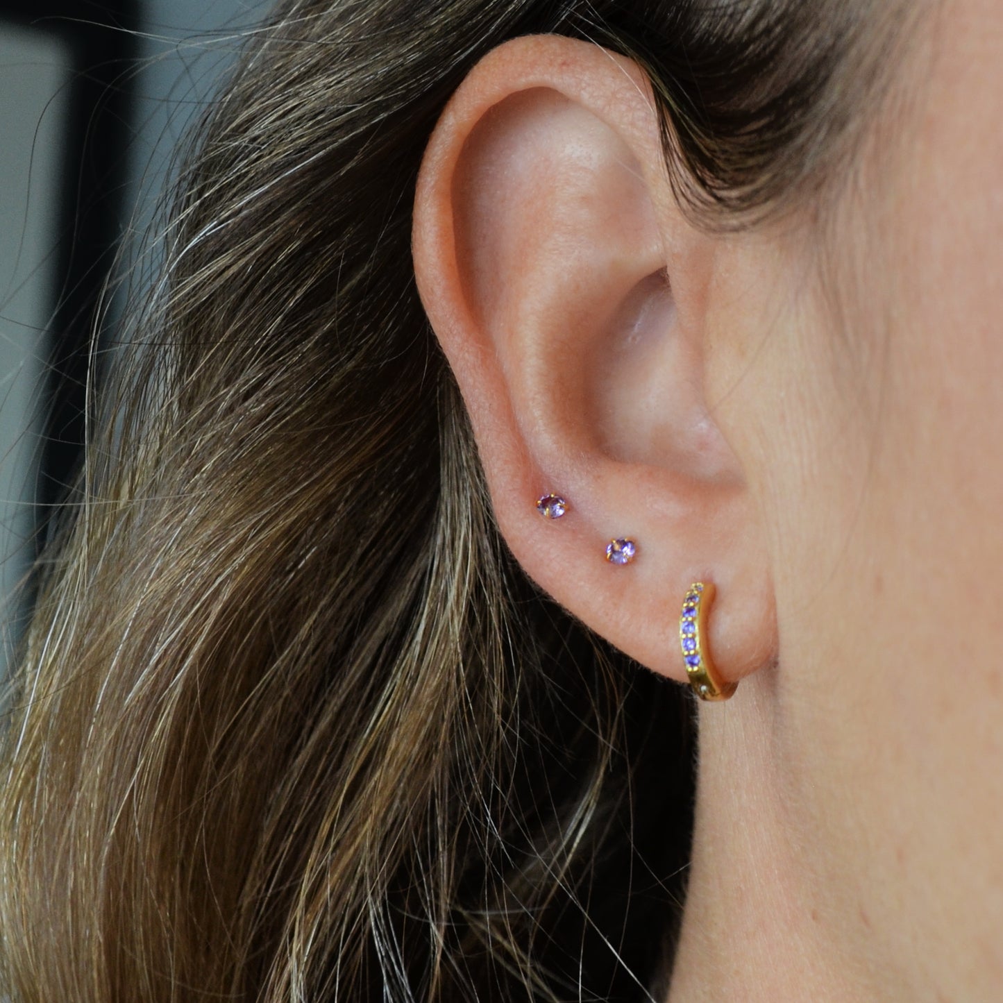 Pequeños pendientes de aro con circonitas lila o moradas confeccionados en plata de ley 925 con baño de oro 18 kilates. Gold plated silver hoop earrings for piercing with lilac zircon