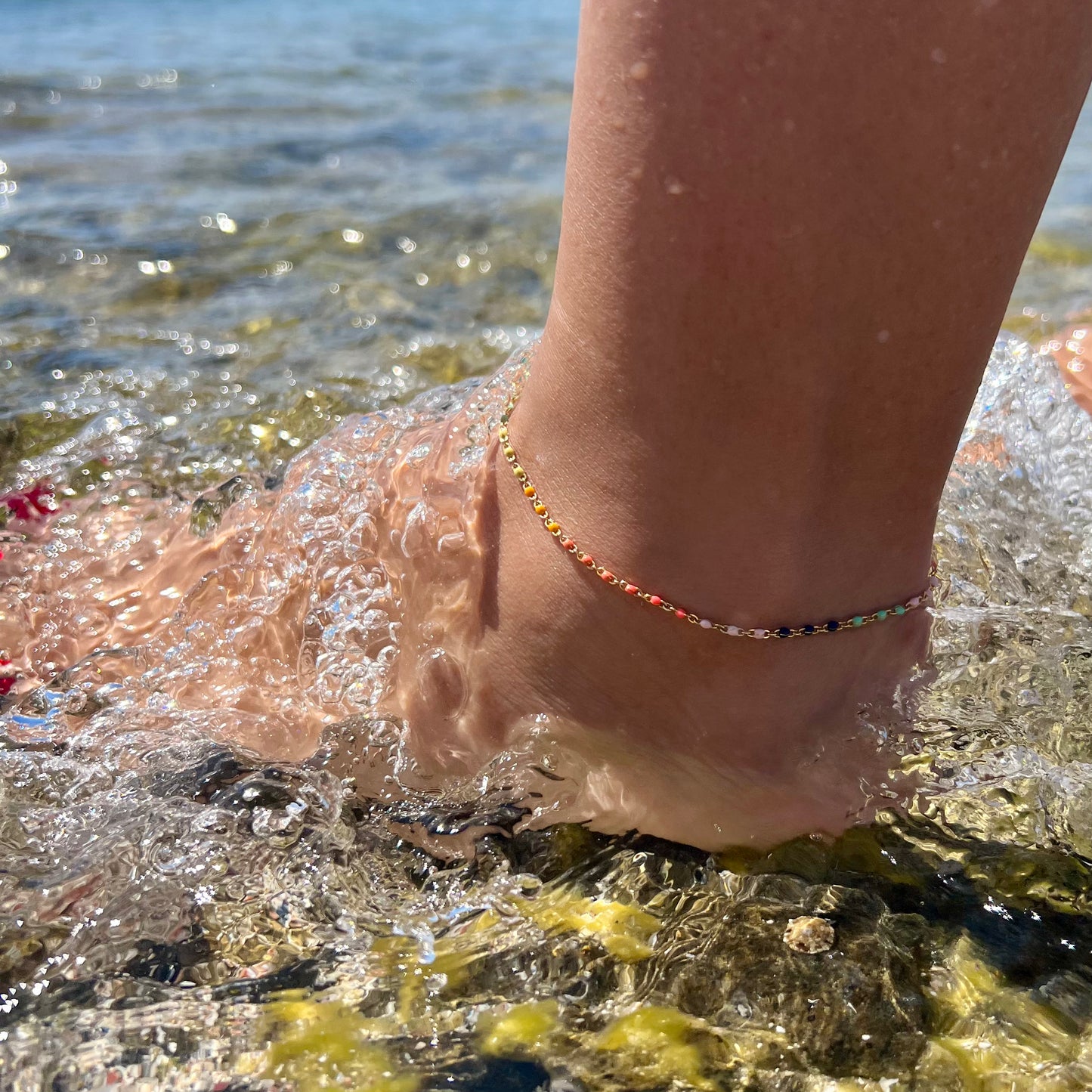 tobillera dorada waterproof o resistente al agua confeccionada en acero con baño de oro de 3 micras. Tiene bolitas de enamel multicolor y el cierre es ajustable