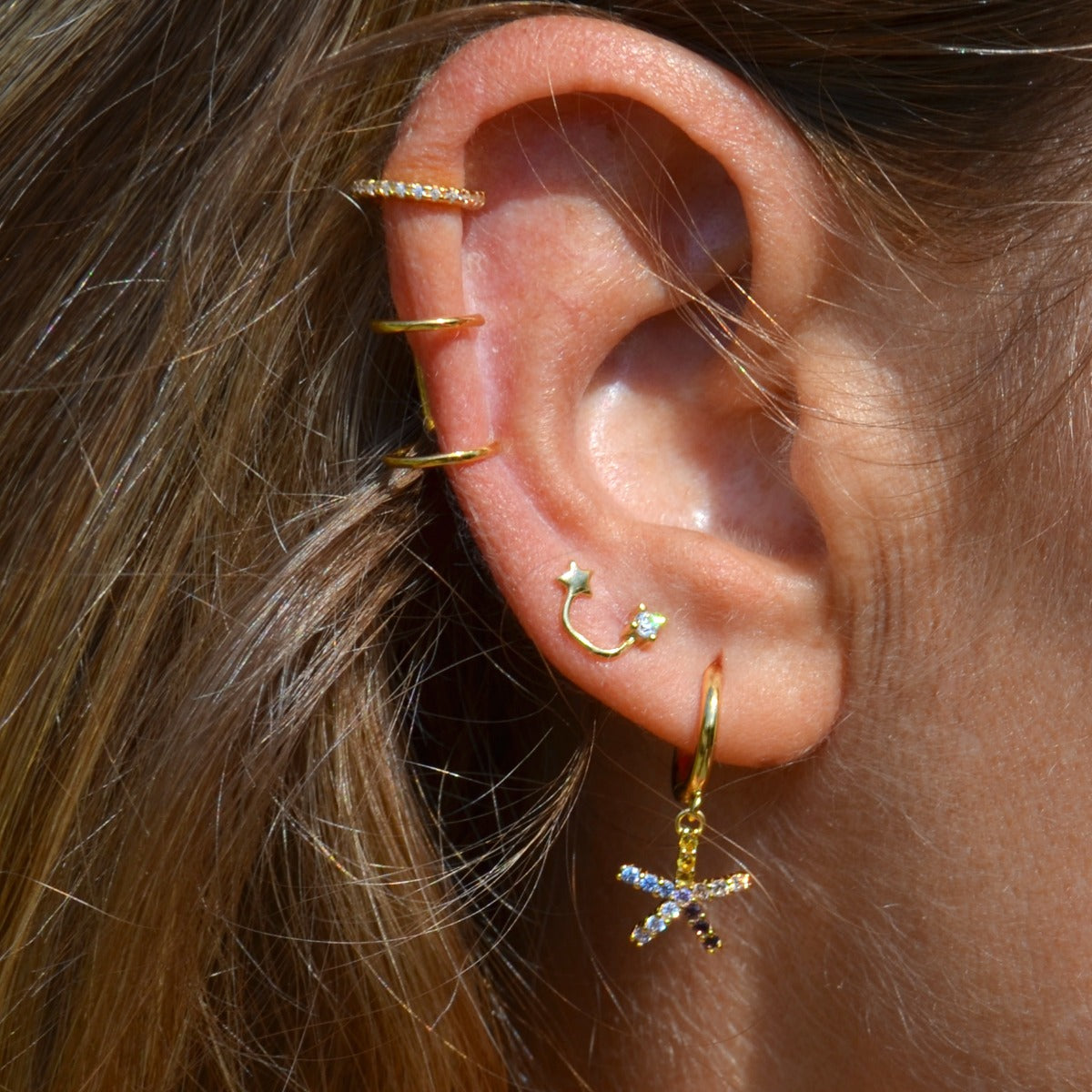 pendientes de aro pequeño con cierre fácil para piercing que tienen un colgante de estrella multicolor y están confeccionados en plata de ley con baño de oro 18 kilates. Gold plated sterling silver color zircon hoop earrings for piercing that are hypoallergenic.