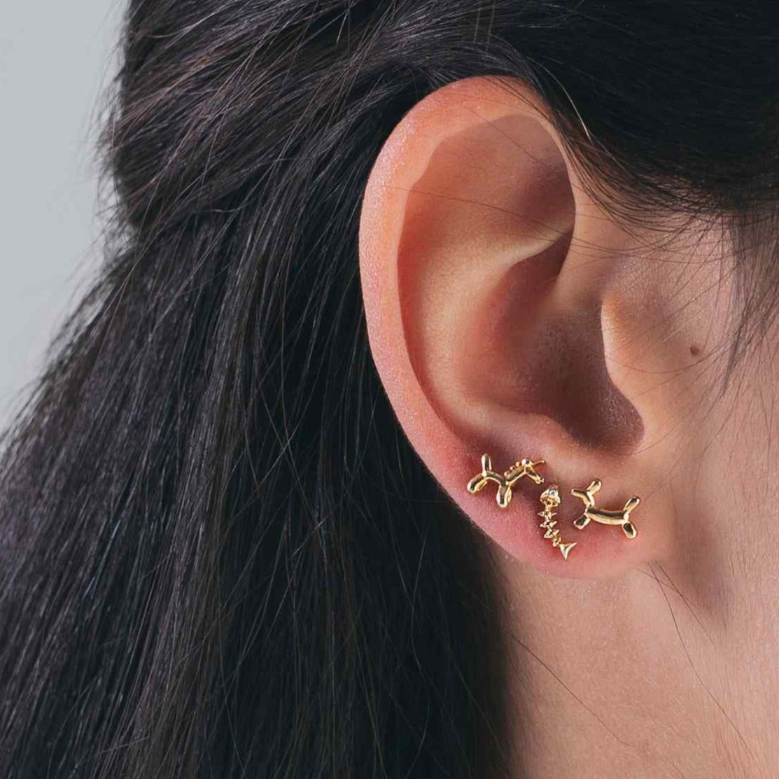 Pendientes pequeños de piercing con forma de raspa de pescado. Son hipoalergénicos o anti alergia porque están confeccionados en plata de ley con baño de oro 18 kilates. Gold plated sterling silver small fish bone piercing earrings.