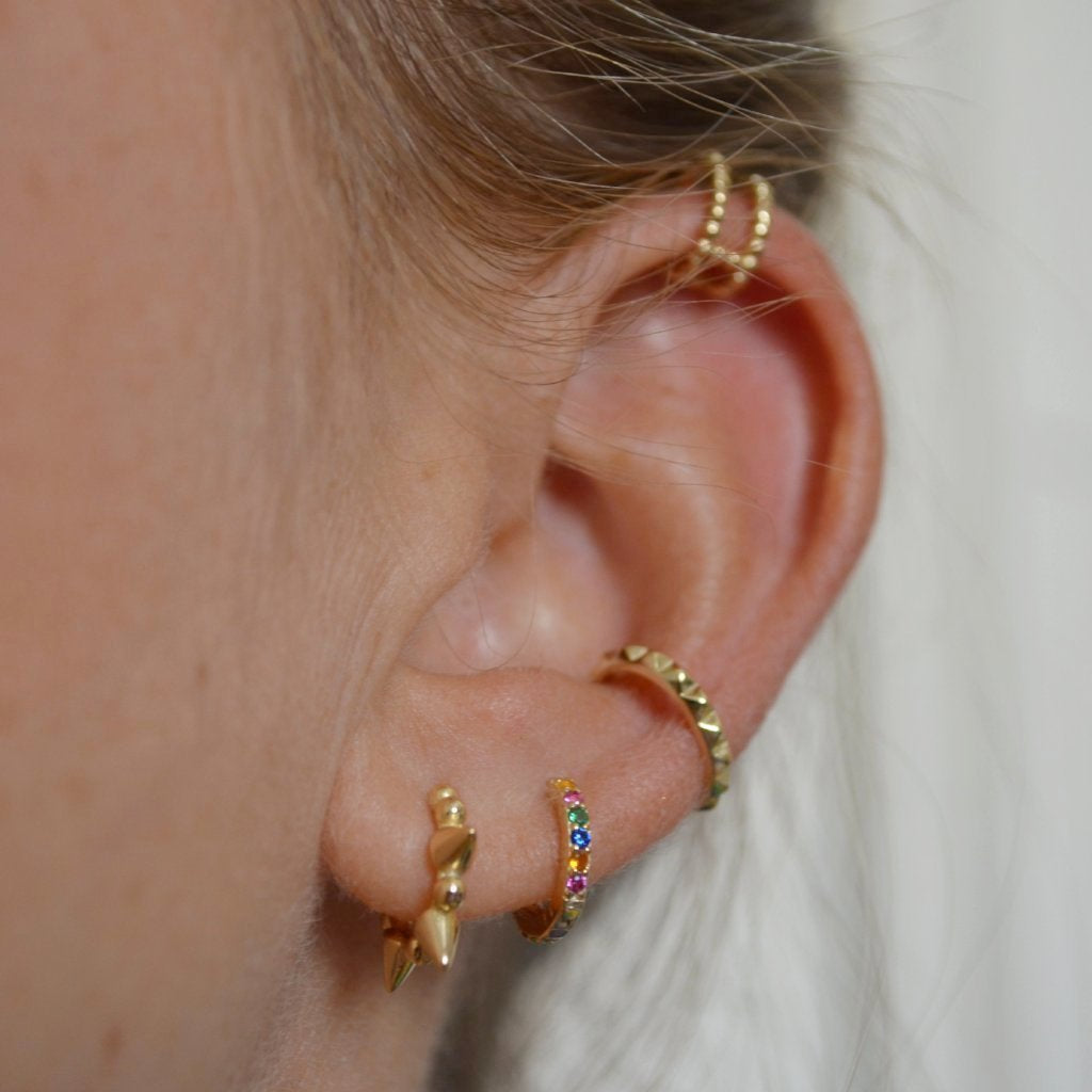 Pequeños pendientes de aro para niña o piercing de helix y tragus con circonitas multicolor confeccionados en plata de ley 925 con baño de oro 18 kilates. Gold plated sterling silver rainbow zircon small hoop earrings for piercing.