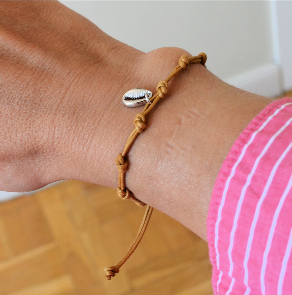 Pulsera para verano con nudos de colores. Está confeccionada en cordón encerado con dos nudos. Se puede personalizar con un colgante de letra o charms de estrella, concha o luna. El cierre es ajustable.