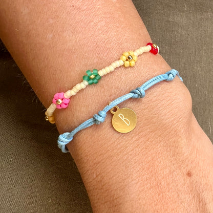 Pulsera para verano con nudos de colores. Está confeccionada en cordón encerado con dos nudos. Se puede personalizar con un colgante de letra o charms de estrella, concha o luna. El cierre es ajustable.