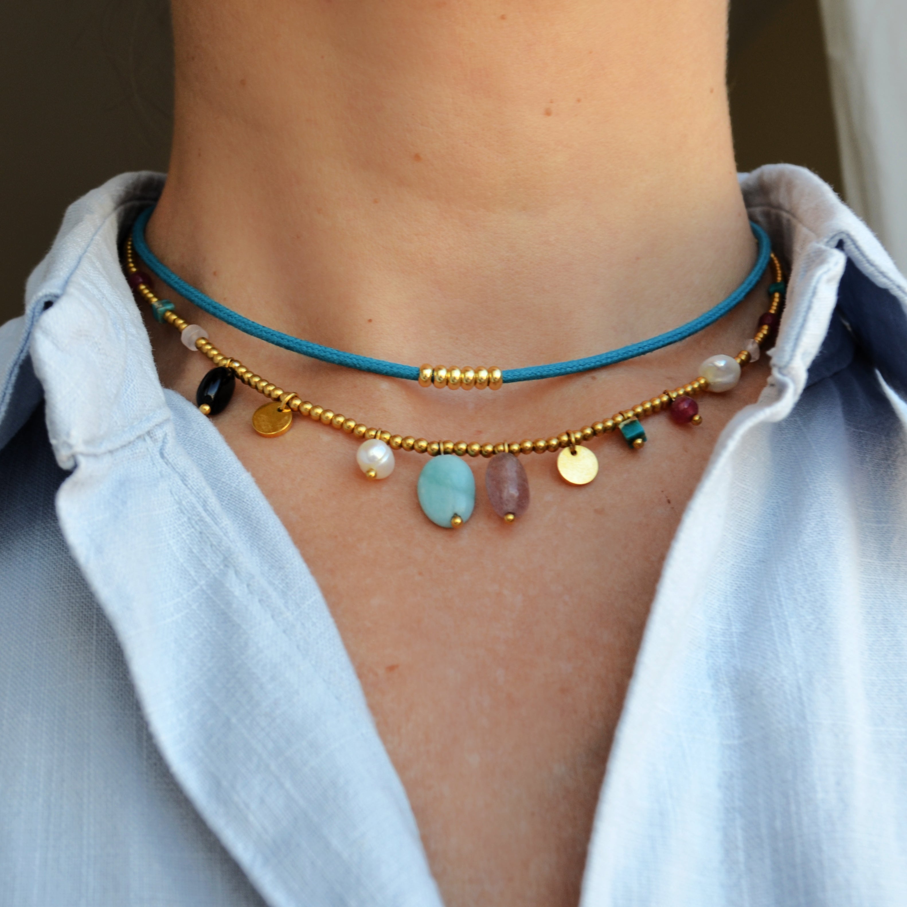COLLAR waterproof o resistente al agua confeccionada en acero con baño de oro 18 kilates. Tiene abalorios de colores imitando piedra natural y perla cultivada. 
