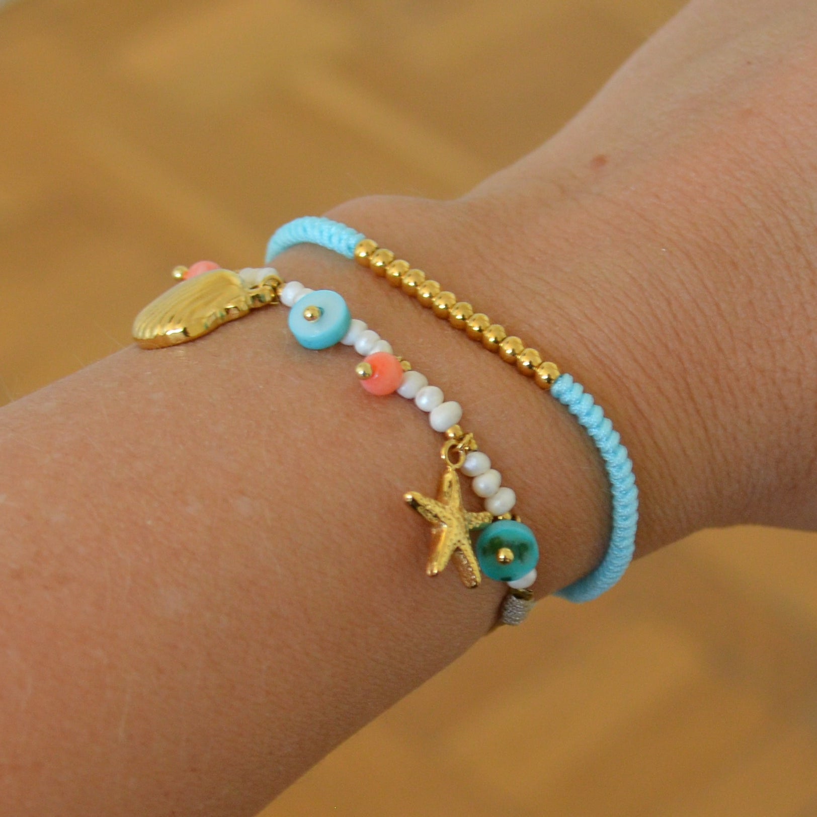 pulsera waterproof o resistente al agua confeccionada con cordón marrón y abalorios de perla, acero con baño de oro 18 kilates.  Cierre ajustable, colgante de concha, caracola, estrella de mar y abalorios de colores (CORAL, azul TURQUESA, naranja)